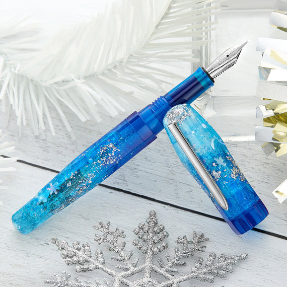 Blue glittery fountain pen on a white surface with decorative snowflakes