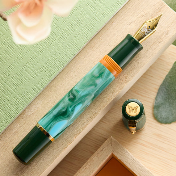 Green fountain pen with gold accents on a wooden surface