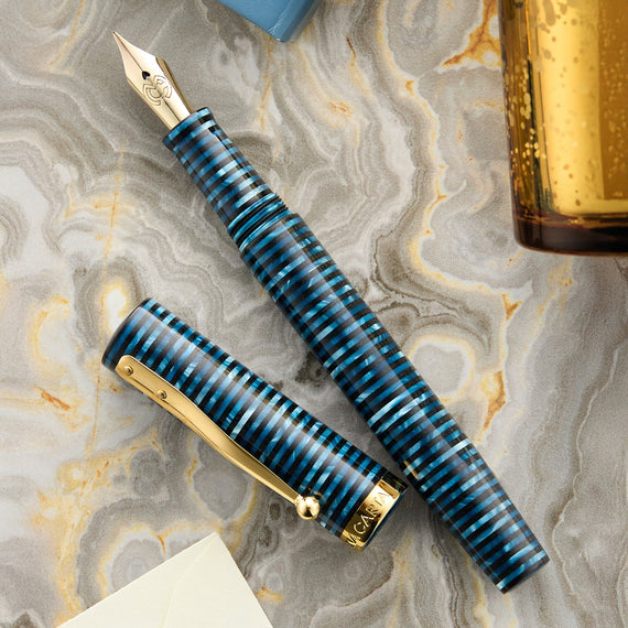 Fountain pen with blue and gold design on a marble surface