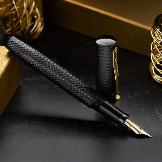 Fountain pen with textured black grip and gold accents on a dark surface
