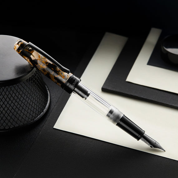 Fountain pen on a black surface with a white paper