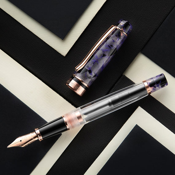 Fountain pen with purple and rose gold accents on a black and white geometric patterned surface