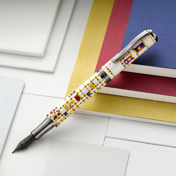 Fountain pen with geometric pattern on a white surface with books in the background
