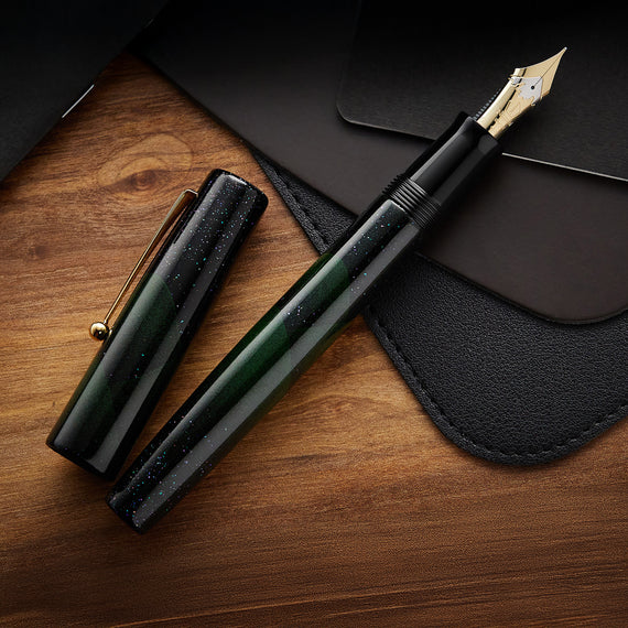 Fountain pen with green body and gold accents on a wooden surface