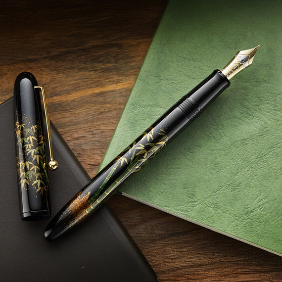 Fountain pen with decorative design on a green notebook and wooden surface