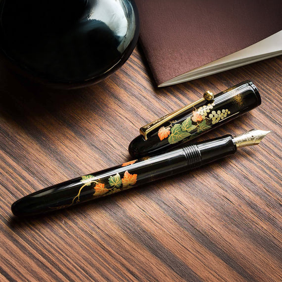 Decorative fountain pen with floral design on a wooden surface