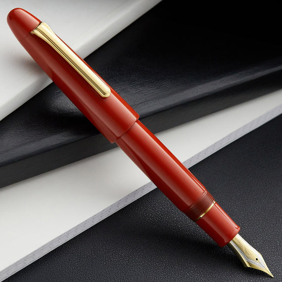 Red fountain pen with gold accents on a black and white background