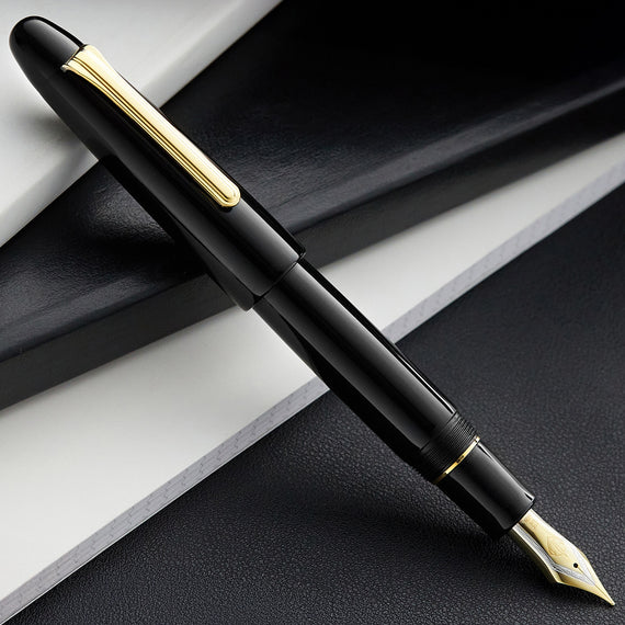 Black fountain pen with gold accents on a dark surface