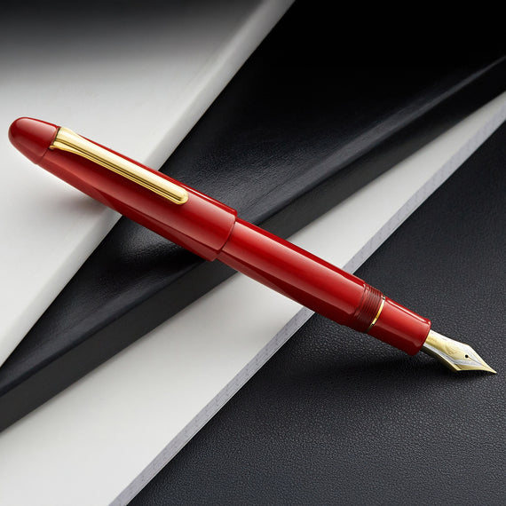 Red fountain pen with gold accents on a black and white background