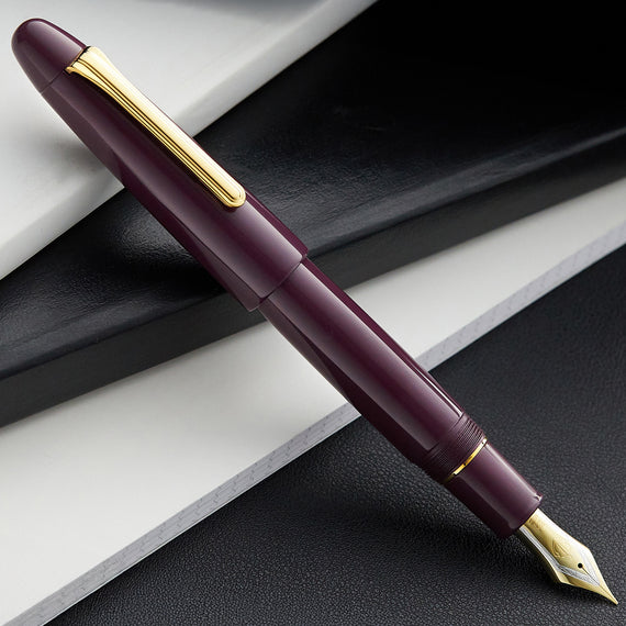 Maroon fountain pen with gold accents on a textured surface