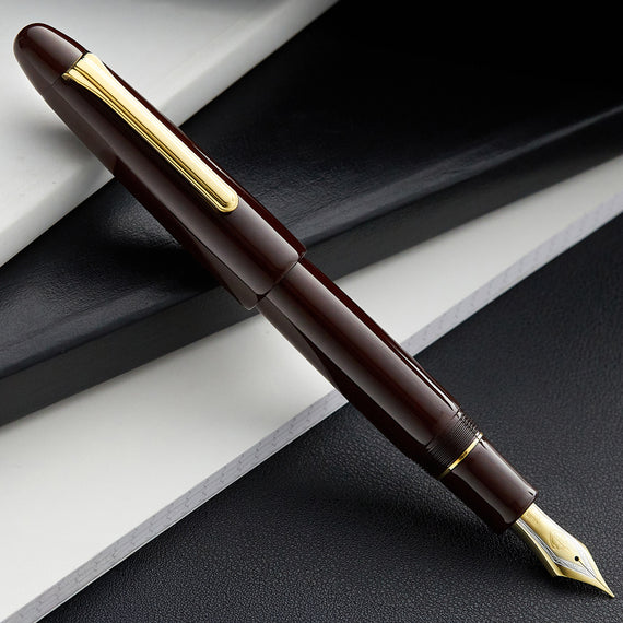 Brown fountain pen with gold accents on a dark surface