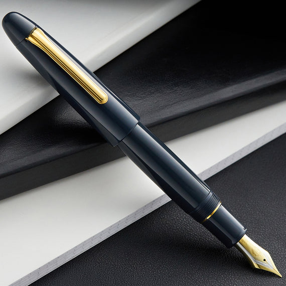 Dark blue fountain pen with gold accents on a dark surface