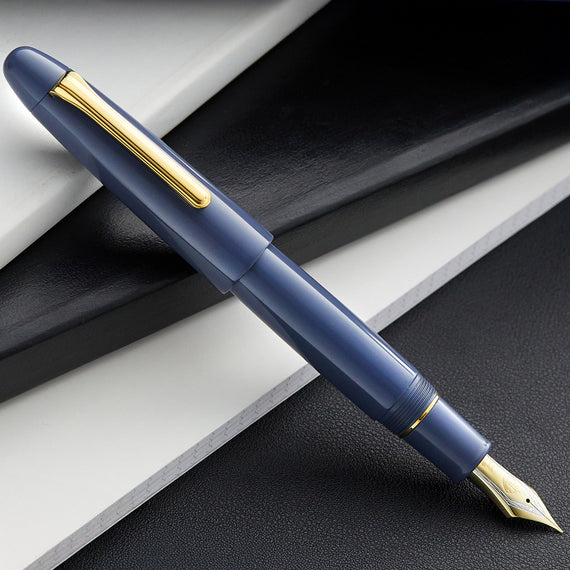 Blue fountain pen with gold accents on a dark surface