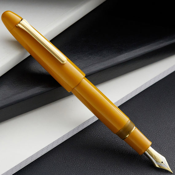Yellow fountain pen with gold accents on a dark surface