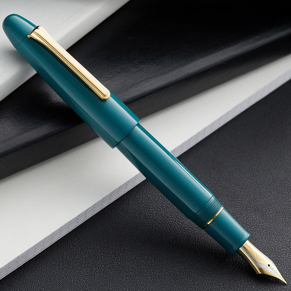 Teal fountain pen with gold accents on a dark surface
