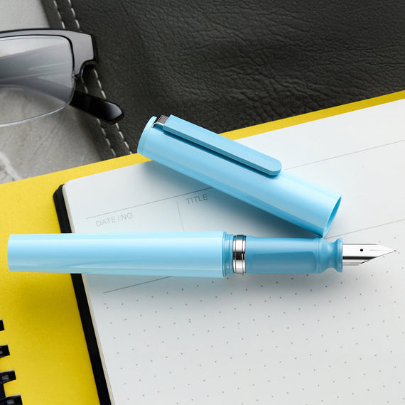 Light blue fountain pen on a notebook with a yellow edge