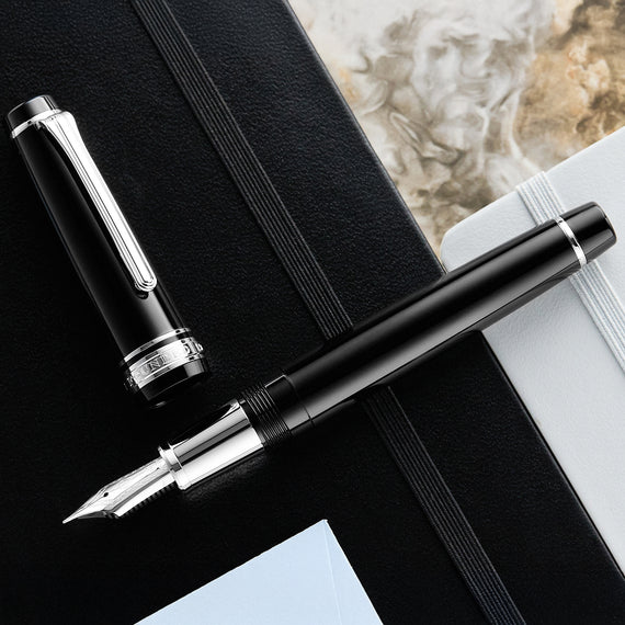 Fountain pen on a black leatherette surface with a marble background