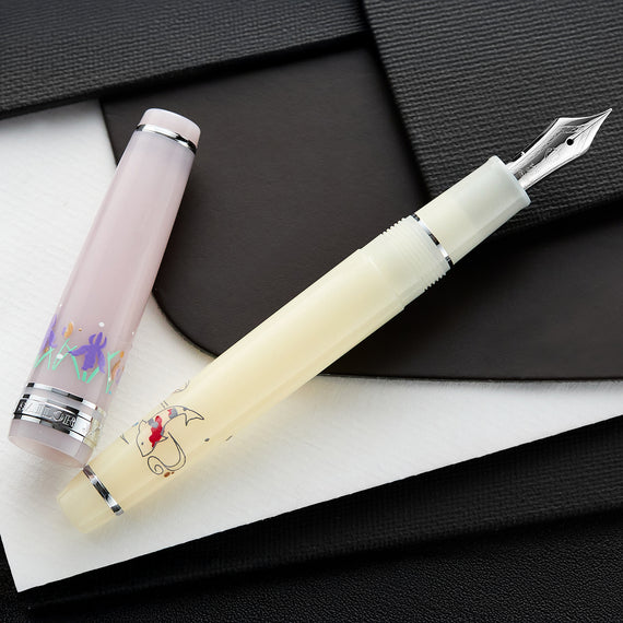 A white and lavender fountain pen with floral design on a black and white textured surface.