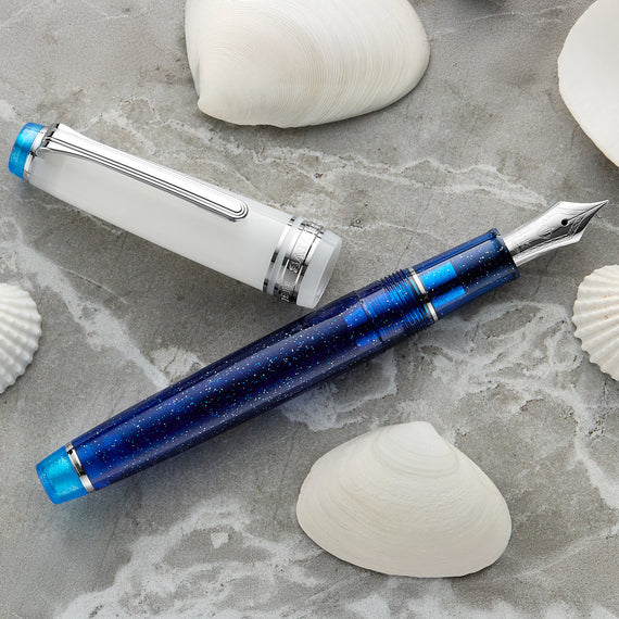 Blue fountain pen on a stone surface with seashells