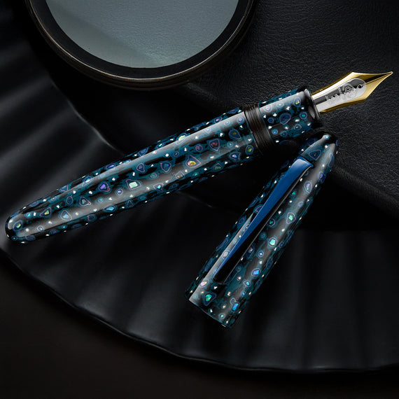 Fountain pen with blue and silver design on a dark surface