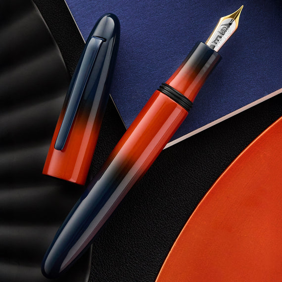 Fountain pen with red and black gradient design on a dark surface