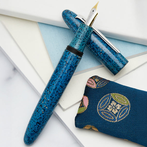 Blue speckled fountain pen with decorative case on a light background